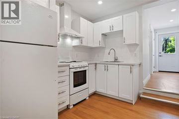 Kitchener apartment for rent - A white kitchen with a refrigerator on the left and a sink under a counter on the right.