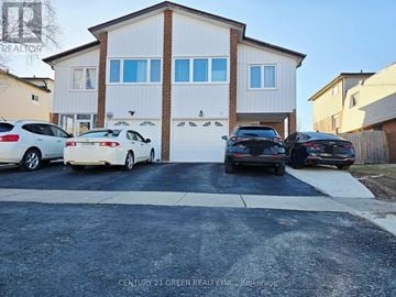Brampton (Brampton North) apartment for rent - A white house with a garage and several cars parked in front.