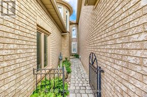 Oakville (Jc Joshua Creek) townhouse for rent - A narrow alleyway between two brick buildings with a metal fence on the left side.