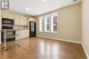 Hamilton (St. Clair) multi-family for rent - A kitchen with wooden floors and a black refrigerator.