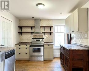 Cobourg apartment for rent - A kitchen with a stove top oven and a range hood.