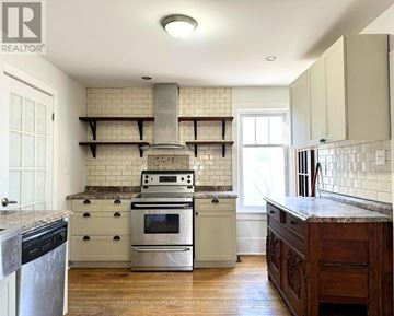 Cobourg apartment for rent - A kitchen with a stove top oven and a range hood.