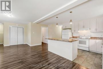 Cornwall triplex for rent - A kitchen with white cabinets and a wooden island.