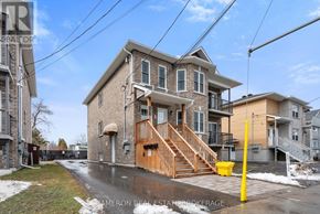 Cornwall triplex for rent - A house with a brown front porch and a yellow post in front of it.