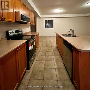 Barrie (Edgehill Drive) apartment for rent - A kitchen with brown cabinets and black appliances.