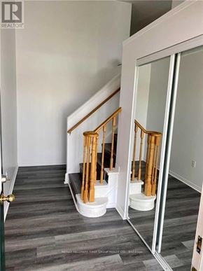 Cobourg townhouse for rent - A hallway with a wooden staircase and a glass door.