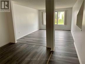 Cobourg townhouse for rent - A spacious room with wooden flooring and white walls.