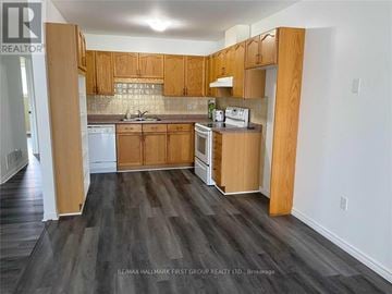 Cobourg townhouse for rent - A kitchen with wooden cabinets and a white dishwasher.