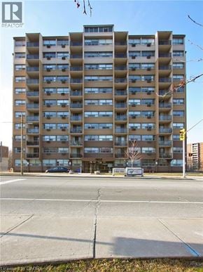 Hamilton condo for rent - A tall apartment building with a white van parked in front.