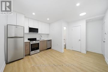 Toronto (O'connor-Parkview) multi-family for rent - A kitchen with white cabinets and a stainless steel refrigerator.
