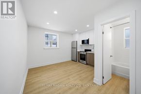 Toronto (O'connor-Parkview) multi-family for rent - A spacious room with a window, a fridge, a microwave, and a stove.
