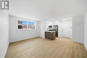 Toronto (O'connor-Parkview) multi-family for rent - A spacious room with a wooden cabinet and a window showing a view of a building.