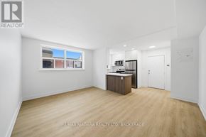 Toronto (O'connor-Parkview) multi-family for rent - A spacious room with wooden flooring and white walls, featuring a kitchenette with a sink and cabinets.