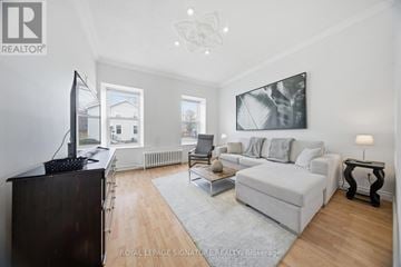 Hamilton (Corktown) triplex for rent - A living room with a white couch and a television.