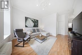 Hamilton (Corktown) triplex for rent - A living room with a grey chair and a white couch.