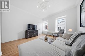 Hamilton (Corktown) triplex for rent - A living room with a grey sofa and a television on a cabinet.