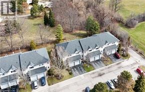 Stoney Creek townhouse for rent - A large white house with a grey roof is surrounded by a parking lot.