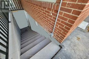 St. Catharines (Port Dalhousie) apartment for rent - A staircase with a metal railing and a brick wall.