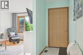 Kitchener apartment for rent - A room with a brown door, a grey chair, and a window with a view of trees.