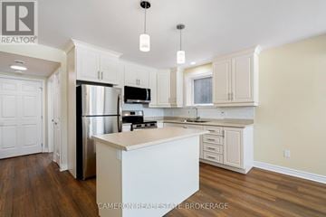 Cornwall triplex for rent - A kitchen with white cabinets and a stainless steel refrigerator.