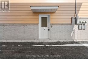 Cornwall triplex for rent - A white door is on the side of a building with a sign that says "Cameron Real Estate Brokerage.".