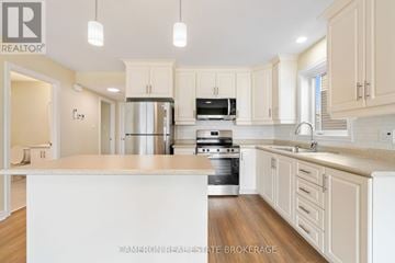 Cornwall triplex for rent - A kitchen with white cabinets and a white island.