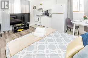 Ottawa apartment for rent - A bedroom with a bed, a TV, a kitchenette, and a dining area.