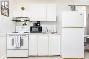 Ottawa apartment for rent - A white kitchen with a refrigerator, oven, microwave, and sink.