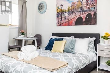 Ottawa apartment for rent - A bedroom with a large bed and a painting of a bridge on the wall.