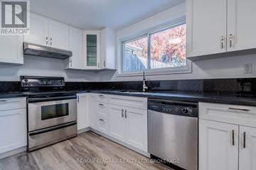 Welland (West Welland) apartment for rent - A kitchen with white cabinets and black countertops.