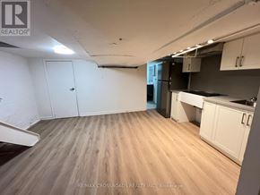Toronto (South Riverdale) apartment for rent - A room with wooden flooring and white walls, with a kitchen area to the right.