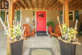 Blue Mountains apartment for rent - A red door is the centerpiece of a wooden porch with two chairs and two planters.