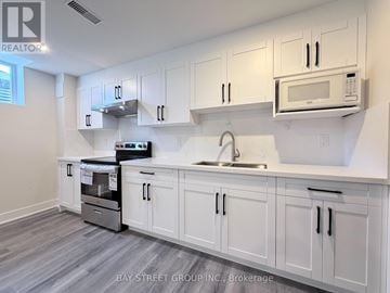 East Gwillimbury (Sharon) apartment for rent - A kitchen with white cabinets and a microwave above the sink.
