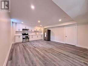 East Gwillimbury (Sharon) apartment for rent - A spacious kitchen with white cabinets and a grey floor.