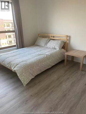 Windsor condo for rent - A bedroom with a bed, pillows, and a small table.