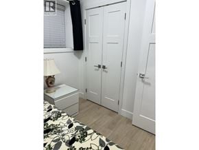 Vancouver townhouse for rent - A white bedroom with a bed, nightstand, and wardrobe.
