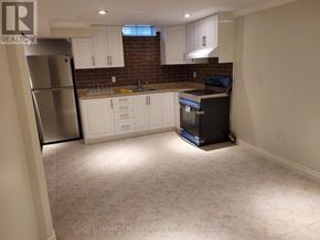 Mississauga (Central Erin Mills) apartment for rent - A kitchen with white cabinets and a brick backsplash is shown.
