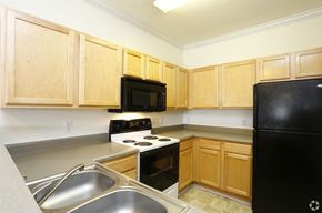 Greenville apartment for rent - A kitchen with wooden cabinets and a black fridge.