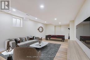 Milton (Co Coates) multi-family for rent - A modern living room with a grey sofa, a coffee table, and a large mirror on the wall.