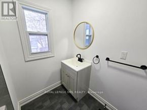 Port Colborne (East Village) fourplex for rent - A bathroom with a white cabinet and a round mirror.