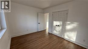 Newmarket apartment for rent - A room with wooden floors and white walls, with a door on the right and a window on the left.