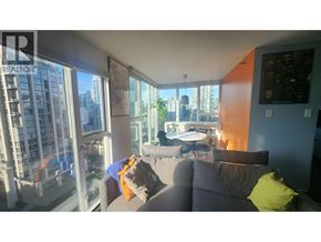 Vancouver apartment for rent - A living room with a grey couch and a large window overlooking a cityscape.