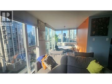 Vancouver apartment for rent - A living room with a grey couch and a large window overlooking a cityscape.
