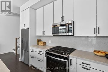 Innisfil townhouse for rent - A kitchen with white cabinets and a black stove top.