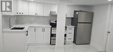 Milton (Be Beaty) apartment for rent - A kitchen with white cabinets and a refrigerator.
