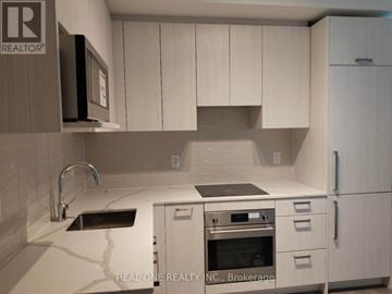 Toronto (Parkwoods-Donalda) townhouse for rent - A kitchen with white cabinets and a black microwave.