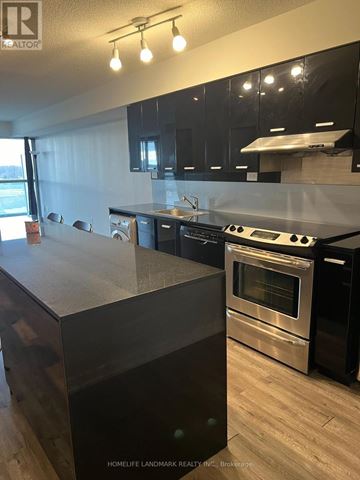 Toronto (Bayview Village) condo for rent - A modern kitchen with black cabinets and stainless steel appliances.
