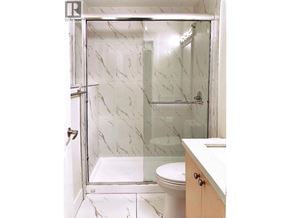 Burnaby apartment for rent - A white marble bathroom with a walk in shower.