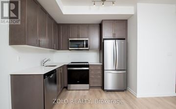Newmarket (Glenway Estates) townhouse for rent - A kitchen with brown cabinets and a stainless steel refrigerator.