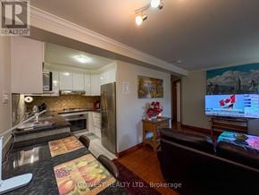 Toronto (High Park North) multi-family for rent - A living room with a brown leather couch and a flat screen TV mounted on the wall.